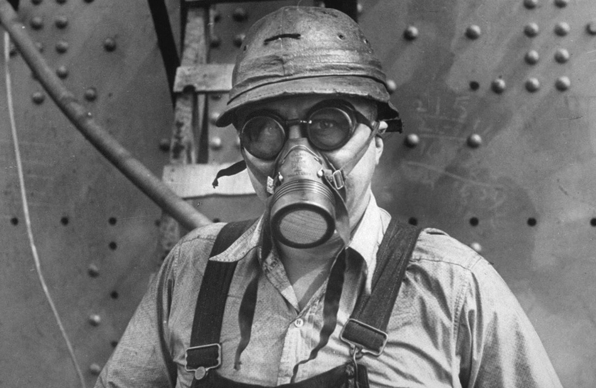 a man in a gas mask looks at the camera in a black and white image