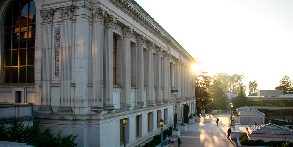 The sun gleams behind Doe Library.
