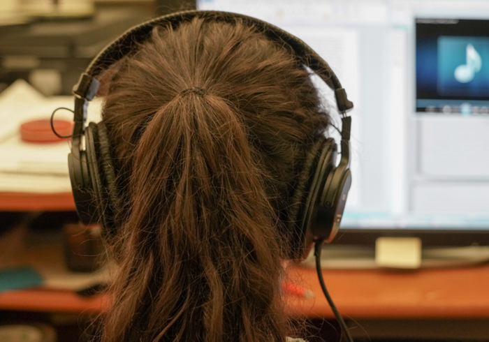 a student looks at a screen while wearing headphones