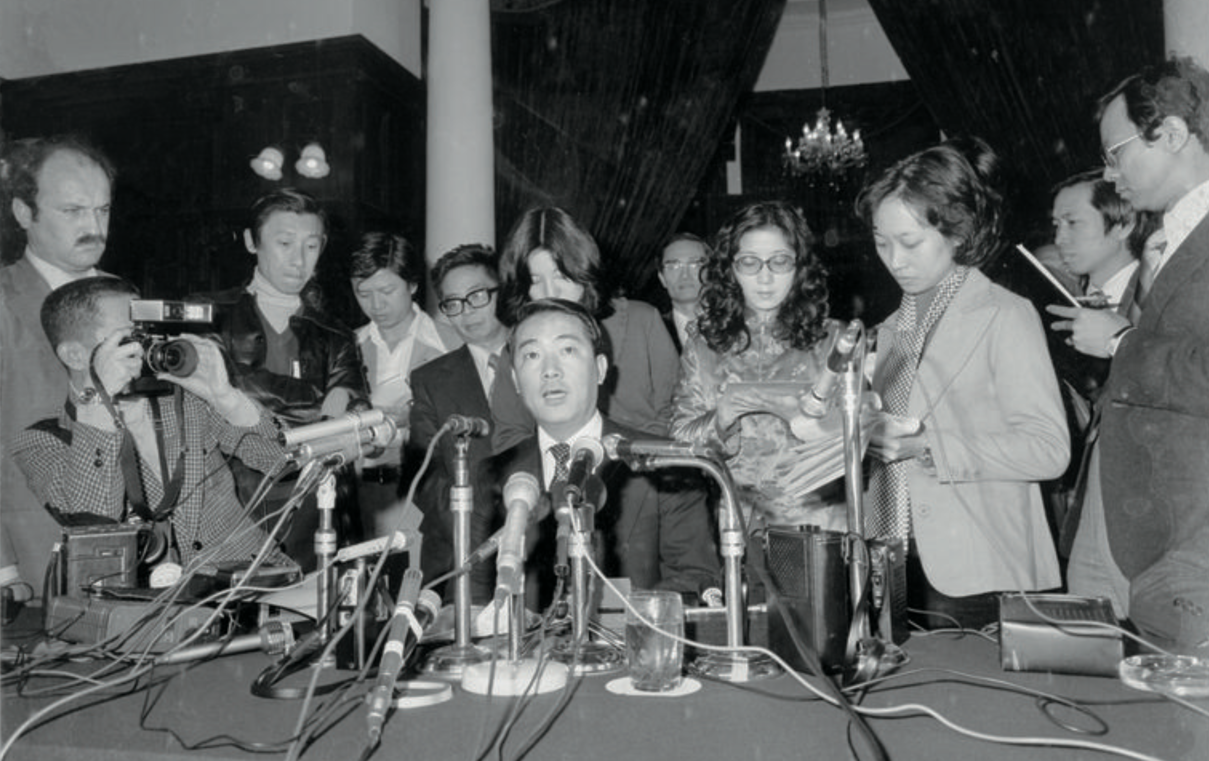 James Soong sits at a table surrounded by reporters in a black and white photo