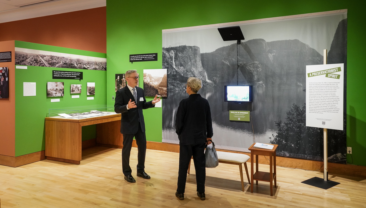 Paul Burnett, director of the Oral History Center, left, chats with a guest at the opening of the “Voices for the Environment” exhibit in The Bancroft Gallery. 