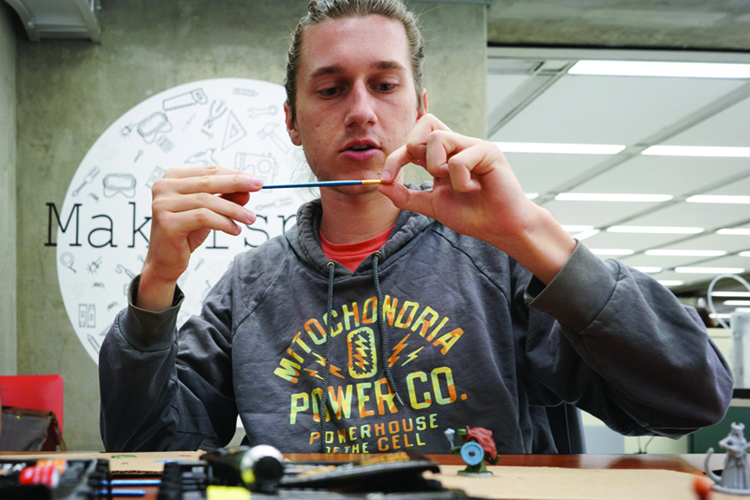 a student paints a small figurine