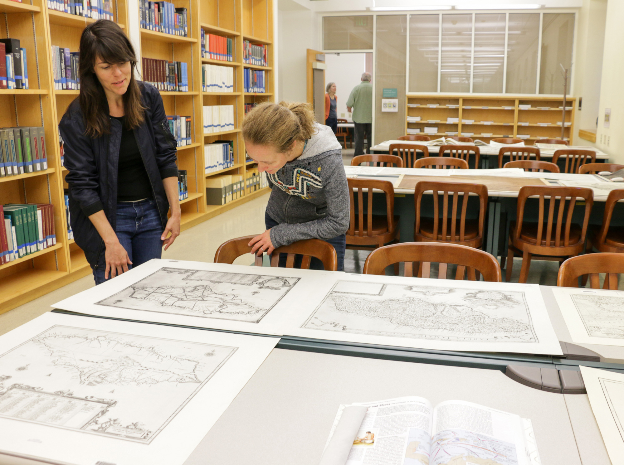 History graduate students Nicole Viglini, left, and Amy O’Hearn discuss Hamilton, in Maps, a pop-up exhibit on display Friday at the Earth Sciences and Map Library. Viglini co-curated the exhibit. (Photo by Jami Smith for the University Library)