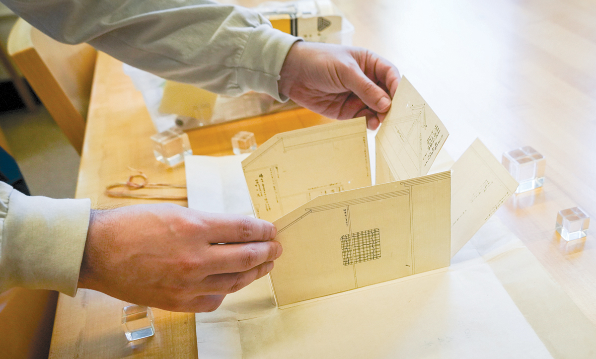 hands open a folded paper building