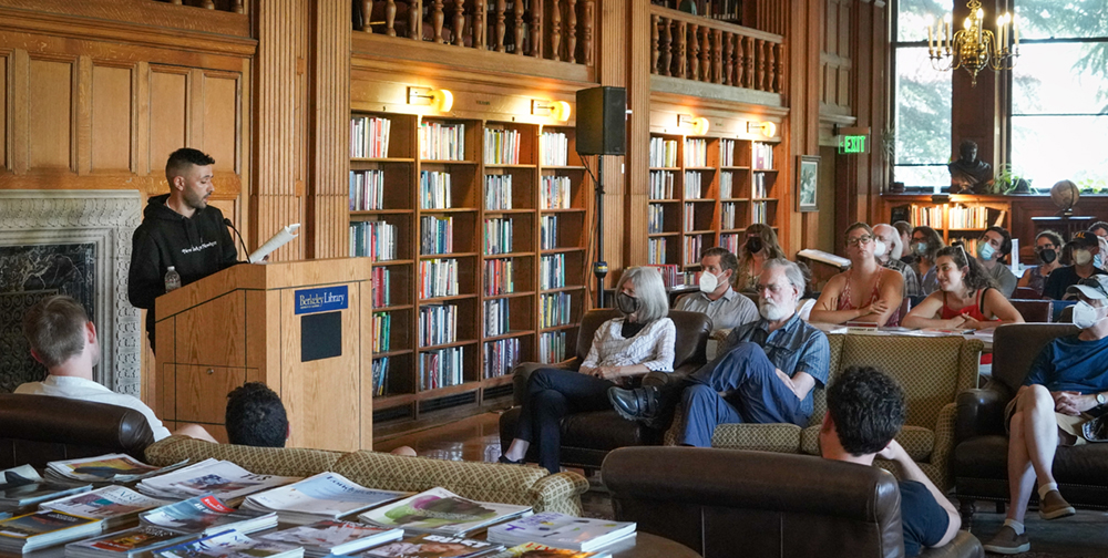 Poet reads his work in a library room filled with people
