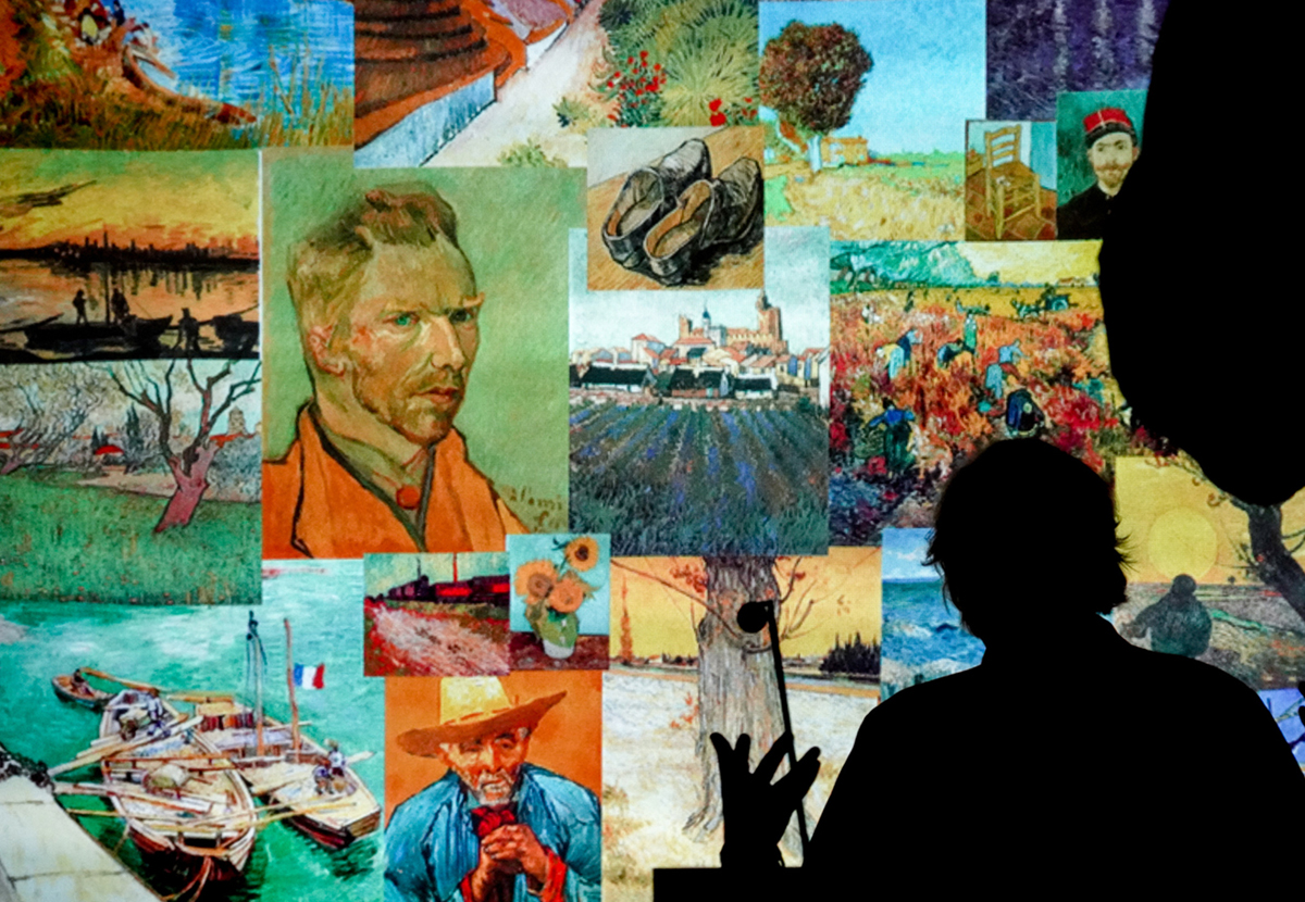 A speaker is silhouetted in front of a display of Van Gogh images