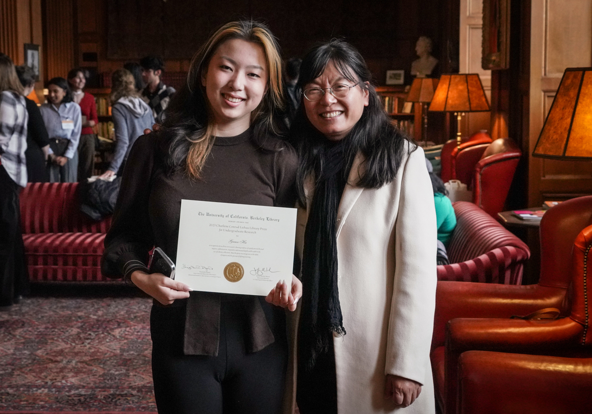 student and librarian pose for a photo with award