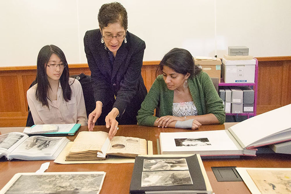 three people look at and discuss books on a table