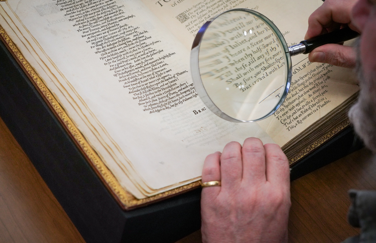 A visitor looks closely at the text with a magnifying glass