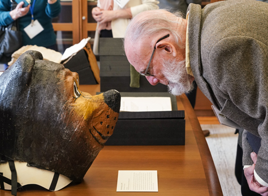 A man looks closely at a bear mask